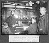 Captain Joseph-Elzéar Bernier and colleagues singing around a pianola in the saloon of C.G.S. ARCTIC. Dr. J.R. Pépin is standin at left 1906