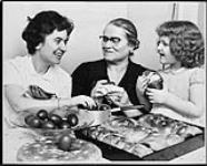 Three generations of Greek-Canadians, Mrs. Aspasoa Sakellaropoulos (centre), her daughter Helen (left) and grand-daughter Magda (right), polishing Easter eggs with olive oil c.a. 16 Apr. 1960