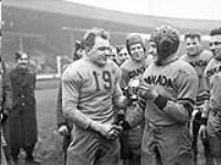 Private First Class Frank Dombrowski (left) of the United States and Major William Denis Whitaker (Canada), rival captains of the teams playing in the Canada-United States "Tea Bowl" football game at White City Stadium, London, England. February 14, 1944.