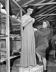 Lieutenant Verity Sweeny adjusting the gown of singer Mary Leonard of the Canadian Army Show, Guildford, England, 21 June 1945 June 21, 1945.
