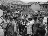 Le capitaine de corvette Fred Day et des officiers du NCSM PRINCE ROBERT en compagnie de prisonniers de guerre canadiens au camp de Shamshuipo August 1945.