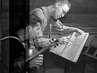 Members of the orchestra of the Meet the Navy Show going over a score, Ottawa, Ontario, Canada, 27 August 1943 August 27, 1943.