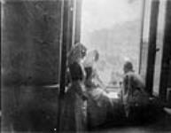 Two nursing sisters with wounded soldier at the Anglo Russian Hospital in the Dmitri Palace. Soldier is in a wheelchair and they are all looking out the window c May 1916