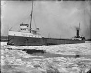 Three-quarters port bow view of laden laker FRANCIS L. ROBBINS, in ice 1923
