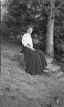 Unidentified woman sitting on tree stump ca. 1907
