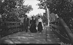 Unidentified group walking over bridge, Lake Rosseau, Muskoka Lakes 1907
