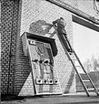 German internee hanging huge electric Victory Loan signboard made by internees at Esterwegen internment camp 30 Ot. 1945