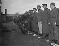 Cameron Highlanders of Ottawa guarding internees at Esterwegen internment camp. Cpl. A. Gordon in charge of Security Patrol, inspects all men in compound for hidden weapons during routine compound patrol 30 Ot. 1945