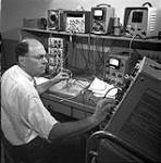 Defence Research Board Laboratories. J.N. Bloom works on designing ground stations which will turn on sounder, record data as Canada's "Topside Sounder" satellite passes over them Mar. 1961