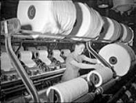 À la manufacture de textiles de la Montreal Cottons, une ouvrière travaille sur une peigneuse c.a. 1945