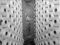 Bobines de fil de coton accrochées à un « ourdissoir », à la fabrique de textiles Montreal Cottons c.a. 1945