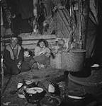 Although the traditional home of the Eskimo is the snow-built igloo, natives of the more southerly regions live in log-walled tents or land-and-mud huts like this one Jan. 1946