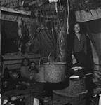 Although the traditional home of the Eskimo is the snow-built igloo, natives of the more southerly regions live in log-walled tents or log-and-mud huts like this one Jan. 1946