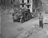 War correspondant James Cassidy standing by the side of the road as trucks and guns move by 17 Aug. 1944