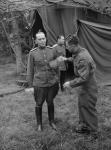 Le bombardier MacDonald brosse l'uniforme du colonel Gorbatov, membre de la mission russe visitant les soldats canadiens en France 28-Jul-44
