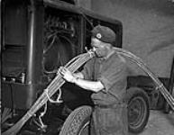 Sapper Fred Hudson with electrical cables connecting generator to the press used to print the first issue of THE MAPLE LEAF 28-Jul-44