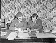 Captains Alan Duckett and Seth Halton censoring copy to be printed in the first issue of the Maple Leaf newspaper, Caen, France, 28 July 1944 July 28, 1944.
