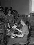 Private Bob Benedict handing copy to linotyper Fred Bell of THE MAPLE LEAF 28-Jul-44