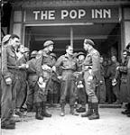 Soldiers standing in front of the new Navy, Army and Air Force Institute (N.A.A.F.I) canteen 'The Pop Inn'. L. to .r: Cpls. John Hay and Abe Granger 27-Jul-44
