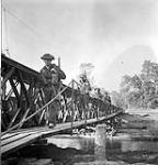 Infantrymen of the Stormont, Dundas and Glengarry Highlanders crossing the Orne River on a Bailey bridge built by the Royal Canadian Engineers (R.C.E.) en route to Caen, France, 18 July 1944 July 18, 1944.