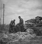 Sergeant N.E. Theriault and Lance-Corporal E.G. Chassie examining a damaged German anti-aircraft gun on the airfield at Carpiquet, France, 12 July 1944 July 12, 1944.