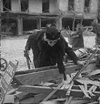 Woman sorting through rubble in search of personal property 11-Jul-44