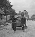 Women pulling a cart with their belongings through the Town Square 11 July. 1944