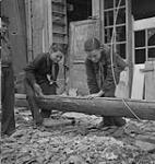 Two Boy Scouts in uniform assisting to clear the debris 11 July. 1944