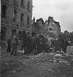 Civilians and soldiers digging out a cart of food from the rubble 10 July. 1944