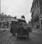 Nuns returning with salvaged belongings in push cart 10-Jul-44