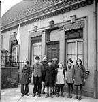 Group of German children in front of home flying white flag duringadvance by No. 1 Canadian Parachute Battalion 4 Apr. 1945