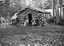 Unidentified group of men, possibly survey party, in front of log cabin 1897