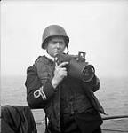 Le lieutenant Gilbert A. Milne, de la Réserve des Volontaires de la Marine royale du Canada, tient un appareil-photo Fairchild K20 June 2, 1944.