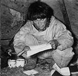 Inuit man [John Pangniq, son of Hijerq] reading a letter written in syllabics 1948.