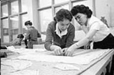Students Nora Arden, left, Dog Rib Indian, and Margaret Gordon, from Aklavik, cut out dress in Home Economics class at Sir John Franklin School Dec. 1959