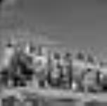 Femmes inuites portant leurs parkas neufs et attendant l'arrivée des passagers du R.M.S. NASCOPIE. [De gauche à droite : Leah Alivaktuk, Evie Anilniliak, Oolanie Akpalialuk, Martha Kanayuk, Ungaaq, Elisapee Naullaalik, Ooloota Kugluguktuk, Ooleepeka Kijuakjuk, Annie Kilabuk, Elisapee Ishulutak, Kilabuk Kooneeluisie, Peelipoosie Kooneeluisie (garçon dans la première rangée).] Aug. 1946
