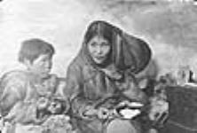 (Femme autochtone coud avec sa fille, Padlei, T.N.-O., 1949-1950). [Kautak (à gauche) et sa mère Atatsiak (à droite). Atatsiak, épouse de  Koomayuak, enseignant la couture à Kautak.] 1949-1950