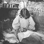 [Elise Qulaut (born Kutikutuk) sewing with her child Elizabeth in a qamaq. Igloolik, N.W.T., 1953.] 1953