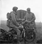 Despatch rider Private J.W. King (left), who is riding a Harley-Davidson motorcycle, accepts a pigeon message from Corporal J. Hanley, Royal Canadian Corps of Signals (R.C.C.S.), England, 10 February 1943 February 10, 1943.