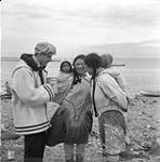 Representative of the Department of Indian Affairs S.J. Bailey explaining the benefits of pablum to two Inuit women with babies 1948