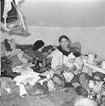 Inuit woman with baby, sewing machine, and clothing 1948
