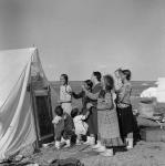 Famille inuite [La femme à gauche est Winnie Qahulrat Attungala] regardant une affiche concernant les allocations familiales 1948.