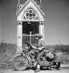 Lance-Corporal Don Fife of No.2 Provost Company, Canadian Provost Corps (C.P.C.), on a motorcycle en route to Falaise. Fresney-le-Puceau, France, 12 August 1944 August 12, 1944.