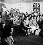 National Film Board of Canada operator showing films at a consolidated school in Alberta. Here pupils see "Target Berlin"; a short about the condition of Indians in this country; and a movie aboutthe Thompson River Feb. 1944