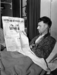 War correspondent Bill Kinmond of the Toronto Daily Star, who is recuperating in hospital after his release from captivity, reads the front page of the Star's issue reporting his capture, Watford, England, 20 April 1945 April 20, 1945
