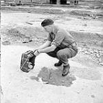 Lieutenant L.E. Labow, 2nd Drilling Company, Royal Canadian Engineers (R.C.E.), checking the fuse of the charge which will demolish former German E-Boat pens, Ostend, Belgium, 21 May 1945 May 21, 1945