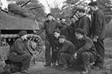 Tank crews of the Canadian Grenadier Guards are briefed on maintenance of the tracks of a Ram tank, England, 24 January 1943 January 24, 1943