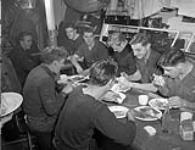 Unidentified crewmen of the minesweeper H.M.C.S. STRATFORD having a meal in their messdeck, St. John's, Newfoundland, November 1943 November 1943.