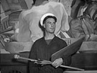 Ordinary Seaman R. Alexander, an artist who painted the mural on naval development at H.M.C.S. DISCOVERY, Vancouver, British Columbia, Canada, 14 June 1945 June 14, 1945