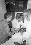 Dr. Crewson, Miss Rundle, Dr. Jordan examining Inuit patient Toodlik in the R.M.S. Nascopie dispensary 1 September 1945.